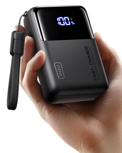 Black power bank with digital display held in a hand on a white background